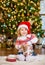 Girl in red santa hat opening gifts near a Christmas tree