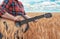 Girl in the red shirt in wheat field plays the acoustic guitar. Beautiful nature at bright sunny summer day.