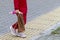 A girl in a red suit with a doll with long hair in her hand is walking along the sidewalk