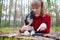 A girl in a red sweater playing with a small German shepherd puppy in the woods