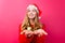 Girl in red sweater, Santa hat and tinsel on neck, holding something invisible on palms isolated on red background.