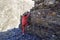 Girl in a red tracksuit climbs over the stone old wall of the destroyed building