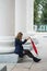 Girl with a red umbrella sits by the columns