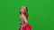 A girl in a red uniform with red pom-poms is dancing in the studio on a green screen. Dancing, acrobatics, gymnastics