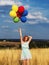 Girl redhead jumping with ballons at the yellow spikelets and blue sky