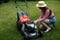 A girl removes the battery from a garden lawnmower.