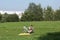 The girl is resting in the park. Sits in a camping chair, looks at the phone. There is a bicycle nearby