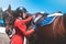 Girl rider adjusts saddle on her horse to take part in horse races