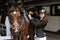 Girl rider adjusts saddle on her horse to take part in horse races