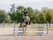 Girl rider on dapple gray horse jumping over a hurdle