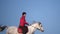 Girl rider rides a white horse in a field . Slow motion