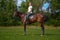 A girl rider trains riding a horse on a spring day