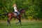 A girl rider trains riding a horse on a spring day