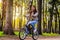 Girl rides a black bicycle in the park among the trees in the rays of the bright sun