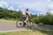 Girl riding a bicycle. Side view. Forest and clouds in the background