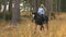 Girl riding on a brown horse through the woods