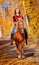 Girl riding horse in the fall time