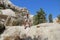 The girl rises by the steep hill by means of rope. Rock formation at the end of the Zemi valley between Gereme and Uchisar, Cappad