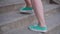 The girl rises up the stairs. Close-up of female legs. On feet of a cool color of shoes.