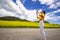 Girl on the road, in a yellow T-shirt, taking a photo in a flowering field, against the backdrop of mountains