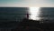 Girl on rocky beach. Young woman standing on ocean cliffs. Girl in red dress at sea. Attractive woman looking at sunset. Beautiful