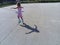 The girl is rollerblading on the asphalt. A 7-year-old child in a striped white and pink dress rides on roller skates on the