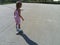The girl is rollerblading on the asphalt. A 7-year-old child in a striped white and pink dress rides on roller skates on the