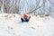A girl is rolling down a snow-covered slide while sitting on a plastic ice floe