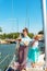 A girl with a rope on the deck of a yacht looks around, and holds the trunks on her shoulder.