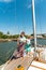 A girl with a rope on the deck of a yacht looks around, and holds the trunks on her shoulder.