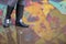 Girl in rubber boots standing in the puddle in the street. Woman in grey rubber boots splashing in a puddle after rain