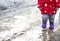 A girl in rubber boots is walking in a puddle. Spring slush.