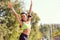 A girl runner smiling raised her hands up in the park.