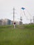 Girl running with flying kite to power line