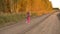 Girl running and twisting on country road autumn evening. Outdoors young girl full length panning.