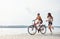 Girl runs near bicycle. Two female friends on the bike have fun at beach near the lake