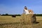 Girl in a rural clothing sitting on the haystack