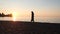 Girl`s evening walk along the seashore at sunset.