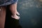 The girl`s feet in the water, surrounded by tadpoles.