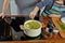 Girl`s hand adding a parsley into the boiling soup. Opened white saucepan on the black stove. Cooking a chicken noodle soup