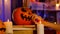 The girl's hand with a brush paints a scary face on a pumpkin. The pumpkin lies on the books next to burning candles in