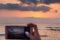 Girl`s hand holding smart phone taking sunset photo on the beach. Mobile phone with sunset view