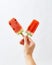 A girl`s hand holds fresh organic slices of watermelon on a stick on a white background with copy space. The concept of