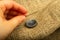 A girl`s hand sewing a black button to a piece of burlap. Close up