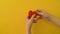 Girl`s hand sews red felt heart, yellow background