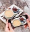 Girl`s hands taking photo of oatmeal porridge with coffe and grated chocolate by smartphone