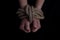 girl& x27;s hands tied with a rope on a black background