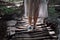 Girl`s legs with backpack walking across hanging bridge in tropical forest