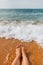 Girl`s legs in the sea water on the sandy shore