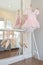 Girl`s pink dress and ballet shoes hang on bar in bedroom